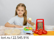 Шестилетняя девочка сидит за кухонным столом перед ней лежат овощи, основа и другие ингредиенты для пиццы. Стоковое фото, фотограф Иванов Алексей / Фотобанк Лори