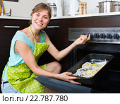 Housewife putting tray with fish in oven. Стоковое фото, фотограф Яков Филимонов / Фотобанк Лори