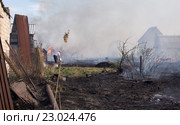 Окраина сада. Пожар. Обгорают саженцы, дома в дыму. Мужчина поливает из вёдер водой не сгоревший участок. Стоковое фото, фотограф Нина Карымова / Фотобанк Лори