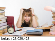 Студентка студит за столом и хитро смотрит в кадр. Стоковое фото, фотограф Иванов Алексей / Фотобанк Лори