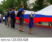 Девочка вместе с взрослыми держит большой флаг России (2015 год). Редакционное фото, фотограф Юлия Олейник / Фотобанк Лори