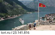 Национальный флаг Черногориии над крепостью St. John на фоне Которской бухты. Туристы на обзорной площадке. Котор, Черногория (2016 год). Стоковое видео, видеограф Кекяляйнен Андрей / Фотобанк Лори