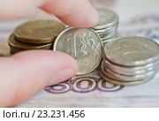 Женская рука берет рублевую монетку. Монеты номиналом в 1, 2, 10 рублей на фоне купюр номиналом в 500 рублей. Стоковое фото, фотограф E. O. / Фотобанк Лори
