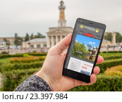 Смартфон в руке, на экране которого туристический портал Костромы (2016 год). Редакционное фото, фотограф Алексей Луковников / Фотобанк Лори