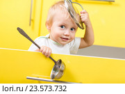 Kid sitting inside yellow opened kitchen box with laddle. Стоковое фото, фотограф Оксана Кузьмина / Фотобанк Лори
