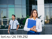 Бизнесвумен стоит возле офиса на фоне мужчины. Стоковое фото, фотограф Виктор Аллин / Фотобанк Лори