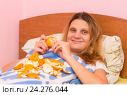 Веселая девушка кушает мандарины, лежа в кровати. Стоковое фото, фотограф Иванов Алексей / Фотобанк Лори
