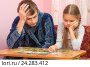 Дочка собирает картинку из пазлов, папа устало сидит рядом и подсказывает ей. Стоковое фото, фотограф Иванов Алексей / Фотобанк Лори