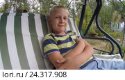Маленький светловолосый мальчик ( 7 лет ) рассуждает, качаясь на дачных качелях на природе. Стоковое видео, видеограф Mikhail Erguine / Фотобанк Лори