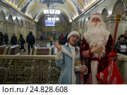 Дед Мороз и Снегурочка дарят подарки пассажирам Московского метрополитена на станции "Комсомольская" Кольцевой линии (2017 год). Редакционное фото, фотограф Николай Винокуров / Фотобанк Лори