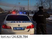 Инспектор ДПС стоит на посту около автомобиля с включенным спецсигналом на набережной города во время общественного мероприятия (2017 год). Редакционное фото, фотограф Николай Винокуров / Фотобанк Лори