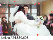 The groom carrying bride in his arms, the crowd throws petals and rice. Happy wedding. Стоковое фото, фотограф Евгений Майнагашев / Фотобанк Лори