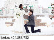 Guy asks the girl hands. Winter wedding, groom on his knee in front of the bride a snowy street. The marriage concept , will you marry me. Стоковое фото, фотограф Евгений Майнагашев / Фотобанк Лори