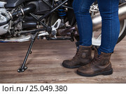 Female legs wearing brown leather safety boots for motorcycling are near motorbike, close up view. Стоковое фото, фотограф Кекяляйнен Андрей / Фотобанк Лори