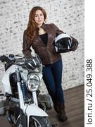 Full-length portrait of female biker holding hand a white open helmet and standing behind the motorbike. Стоковое фото, фотограф Кекяляйнен Андрей / Фотобанк Лори