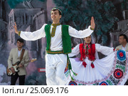 Парень из фольклорно-танцевального ансамбля в национальной таджикской одежде выступает на сцене во время празднования Навруза в парке города Худжанд, Республика Таджикистан (2015 год). Редакционное фото, фотограф Николай Винокуров / Фотобанк Лори