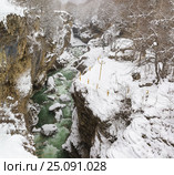 Бурлящая зеленая вода реки Белой в районе оборудованной безопасными ограждениями для туристов Хаджохской теснины в морозный снежный зимний день.Поселок Каменномостский, Республика Адыгея. Стоковое фото, фотограф Наталья Гармашева / Фотобанк Лори
