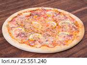 Hot pizza slice with melting cheese on a rustic wooden table. Стоковое фото, фотограф Aleksandr Ryzhov / Фотобанк Лори