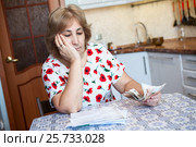 Женщина с грустью смотрит на квитанции по оплате коммунальных платежей. Стоковое фото, фотограф Кекяляйнен Андрей / Фотобанк Лори