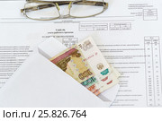 Конверт с рублевыми купюрами разного достоинства и очки лежат на табеле учета рабочего времени. Стоковое фото, фотограф Наталья Гармашева / Фотобанк Лори