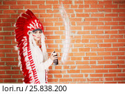 Young woman dressed in costume made of red and white feathers paints on the brick wall with spray. Стоковое фото, фотограф Losevsky Pavel / Фотобанк Лори