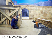 MOSCOW, RUSSIA - MAR 24, 2015: Girl (with model release) with machinegun hides behind wooden box in Optical Illusions Museum at VDNKh. Редакционное фото, фотограф Losevsky Pavel / Фотобанк Лори