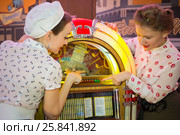 Two girls in retro dress press button on old-fashion musical mac. Стоковое фото, фотограф Losevsky Pavel / Фотобанк Лори