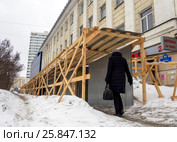 Человек входит в защитное сооружение над тротуаром у реконструируемого здания (2017 год). Редакционное фото, фотограф Вячеслав Палес / Фотобанк Лори