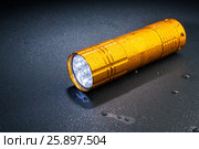 Pocket LED flashlight in the rain on a dark surface. Water drops. Стоковое фото, фотограф Alexander / Фотобанк Лори