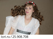Pretty young woman in roses wreath and white dress lies on bed. Стоковое фото, фотограф Светлана Додух / Фотобанк Лори