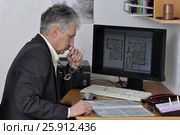 Инженер-архитектор у компьютера, за рабочим столом задумался перед документами (2017 год). Редакционное фото, фотограф Сергей Галинский / Фотобанк Лори