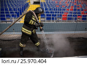 Сотрудник МЧС в полной экипировке принимает участие в учениях по тушению зажженного фанатами фальшфейера на футбольном стадионе ЦСКА в городе Москве, Россия (2017 год). Редакционное фото, фотограф Николай Винокуров / Фотобанк Лори