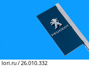 Официальный дилерский знак автомобильного концерна Peugeot на фоне голубого неба. Редакционное фото, фотограф FotograFF / Фотобанк Лори