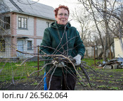 Пожилая женщина держит в руках охапку обрезанных веток. Стоковое фото, фотограф Вячеслав Палес / Фотобанк Лори
