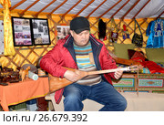 Калмыцкий мужчина играет на домбре  в помещении музея ойрат-монгольской кочевой культуры. Элиста, Калмыкия (2017 год). Редакционное фото, фотограф Ирина Борсученко / Фотобанк Лори