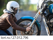 Девушка в мотоциклетном шлеме держится за колесо мотоцикла смотрит на фару. Стоковое фото, фотограф Кекяляйнен Андрей / Фотобанк Лори