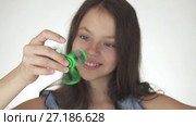 Beautiful cheerful teen girl playing with green fidget spinner on white background stock footage video. Стоковое видео, видеограф Юлия Машкова / Фотобанк Лори