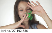 Beautiful cheerful teen girl playing with green fidget spinner on white background stock footage video. Стоковое видео, видеограф Юлия Машкова / Фотобанк Лори