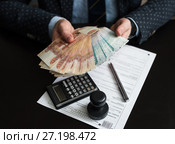 Бизнесмен рассчитывает деньги для оплаты налогов на фоне декларации на вменённый доход. Стоковое фото, фотограф Игорь Низов / Фотобанк Лори