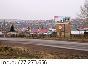 Приветственный щит перед въездом в город Ужур с юга, на фоне частных домов (2017 год). Редакционное фото, фотограф Светлана Попова / Фотобанк Лори