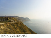 Люди гуляют по дороге вдоль обрывистого морского берега. Окрестности курортного города Анапы в туманный осенний день (2017 год). Редакционное фото, фотограф Наталья Гармашева / Фотобанк Лори