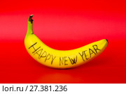 Спелый банан с надписью "Happy new year"  на красном фоне. Стоковое фото, фотограф V.Ivantsov / Фотобанк Лори
