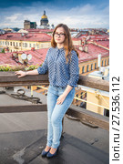 Leggy long-haired lass wearing blue jeans and blouse stands on the roof of the building (2017 год). Стоковое фото, фотограф Сергей Дубров / Фотобанк Лори