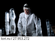 Speleologist in a cave looks at the ice structures, against a dark background. Стоковое фото, фотограф Евгений Харитонов / Фотобанк Лори