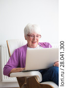 Portrait of a senior woman at home - Laughing at something on her laptop computer, sitting in her favorite chair, enjoying retirement. Стоковое фото, фотограф Viktor Cap / PantherMedia / Фотобанк Лори