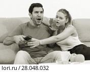 Couple on sofa quarreling because of TV remote. Стоковое фото, фотограф Яков Филимонов / Фотобанк Лори
