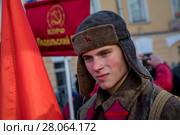 Мужчина с красным знаменем и в форме красноармейца времен Великой Октябрьской революции участвует в марше и митинге КПРФ в честь празднования 100-летне годовщины создания Красной армии в Москве, Россия (2018 год). Редакционное фото, фотограф Николай Винокуров / Фотобанк Лори