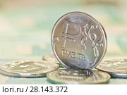 Деньги. Один российский рубль (крупный план) среди других монет на фоне однотысячных купюр. Стоковое фото, фотограф E. O. / Фотобанк Лори