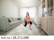 Woman with little baby in hands on her knee in the room. Стоковое фото, фотограф Losevsky Pavel / Фотобанк Лори