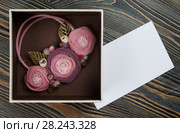 Pink-colored handmade necklace putted in a box and a letter of congratulations are lying on wooden background. Стоковое фото, фотограф Олег Белов / Фотобанк Лори